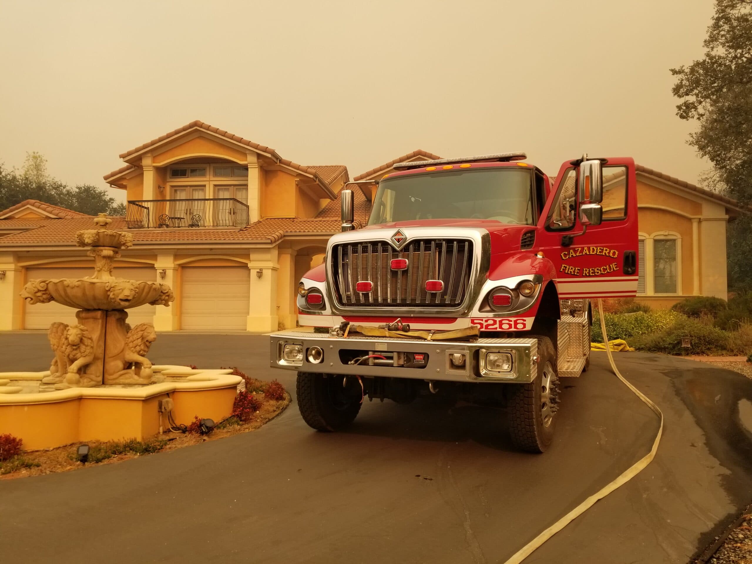 Cazadero Fire Rescue engine staged in front of a home during a wildfire, part of founder Juan de la Cruz's firefighting service
